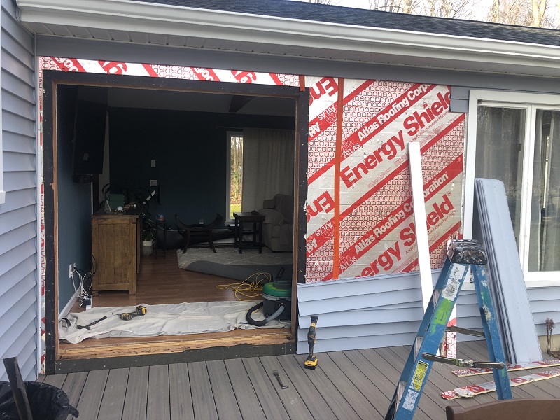 Removing vinyl siding to install this Harvey patio door in Danbury